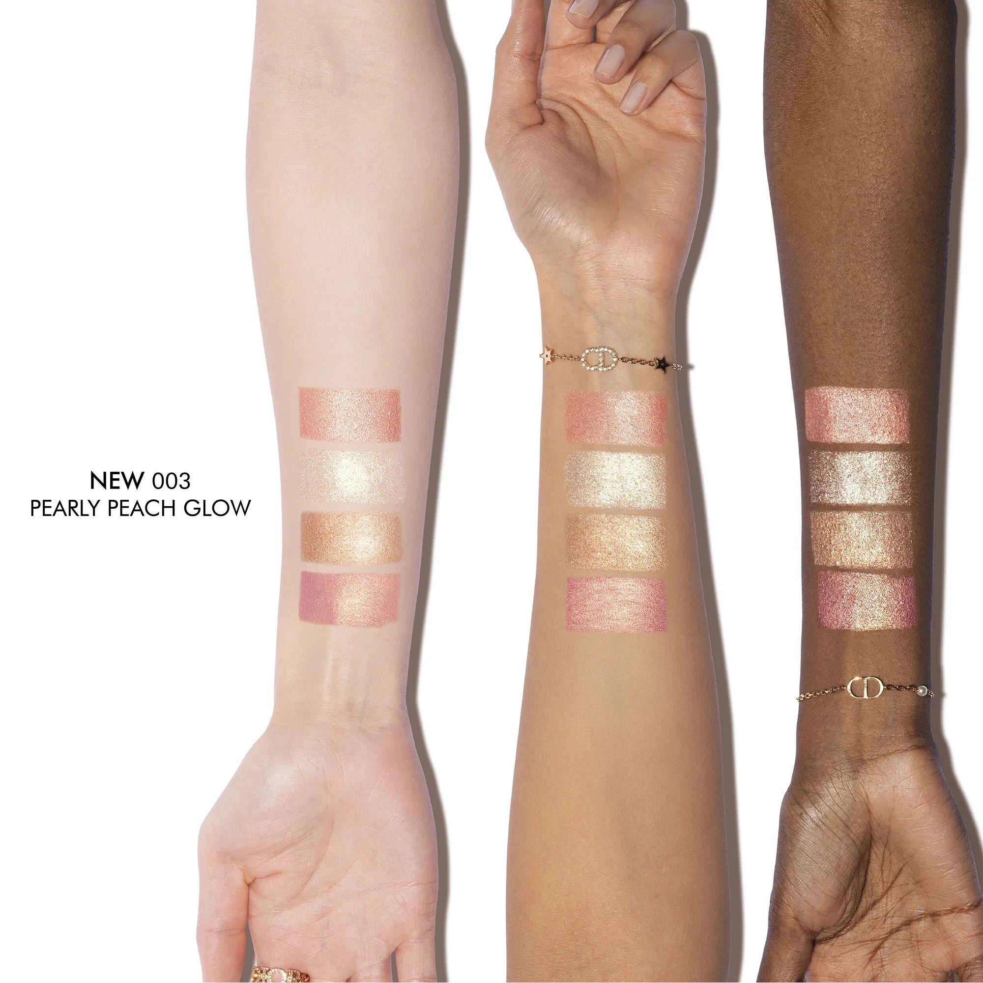 Three arms with different skin tones displaying makeup swatches of a new product labeled 'NEW 003 Pearly Peach Glow'.