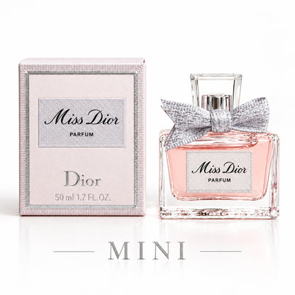 Dior Miss Dior Parfum bottle with a silver bow next to its light pink packaging box on a white background.