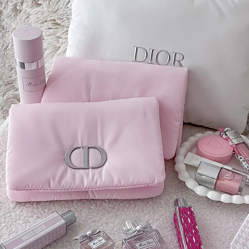 Pink Dior cosmetic bag with various Dior products on a textured surface