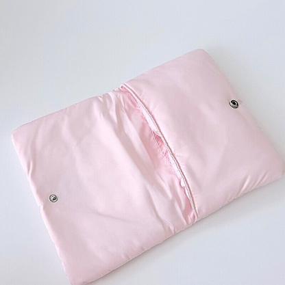 A folded light pink quilted blanket or comforter with two silver metal snap buttons, shown on a plain white background.