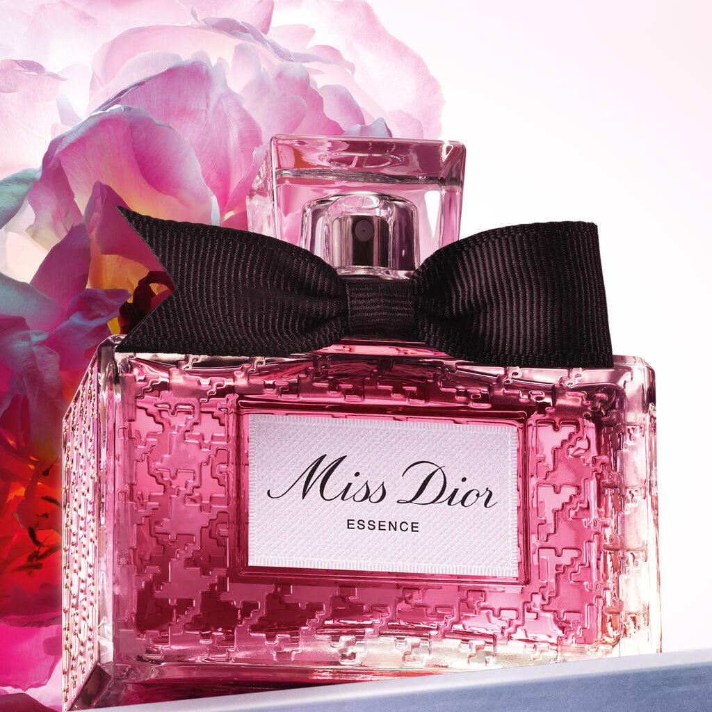 Pink Dior perfume bottle with a black bow and pink flowers in the background