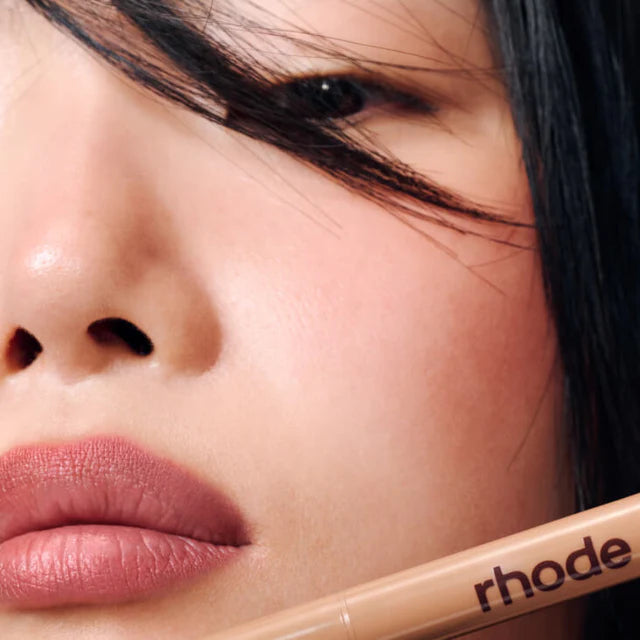 Close-up of a person's face with a Rhode makeup product on the lip.