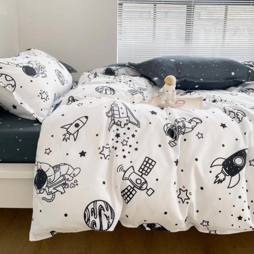 A single-sized bedding set with a white duvet cover and black fitted sheet, featuring a space-themed print with various rockets and planets.