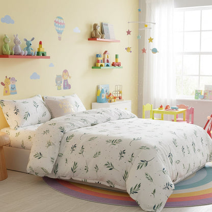 Floral patterned bedding set on a bed in a bedroom with a lamp and plant.