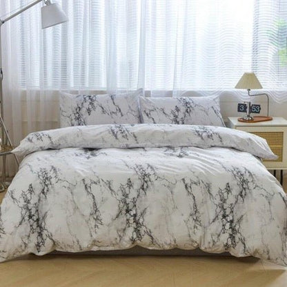 A king-size bedding set with a marble design displayed on a bed in a bedroom setting